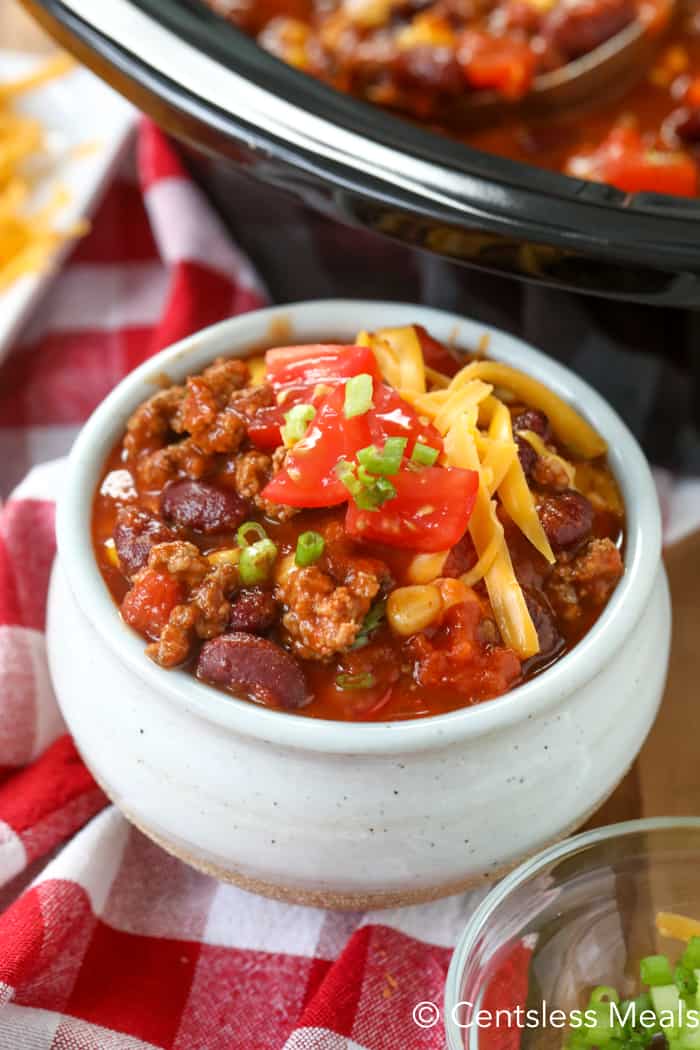 Crock-Pot taco chili in a bowl topped with shredded cheese tomato and chives