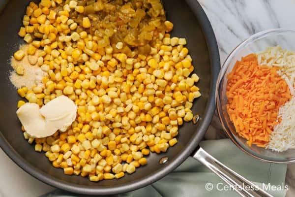 Ingredients for corn casserole in a frying pan and in a glass bowl on a marble board