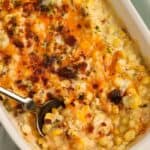 Corn casserole in a white casserole dish with a spoon