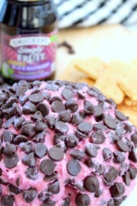 Black raspberry chocolate chip cheese ball with crackers and jam in the background