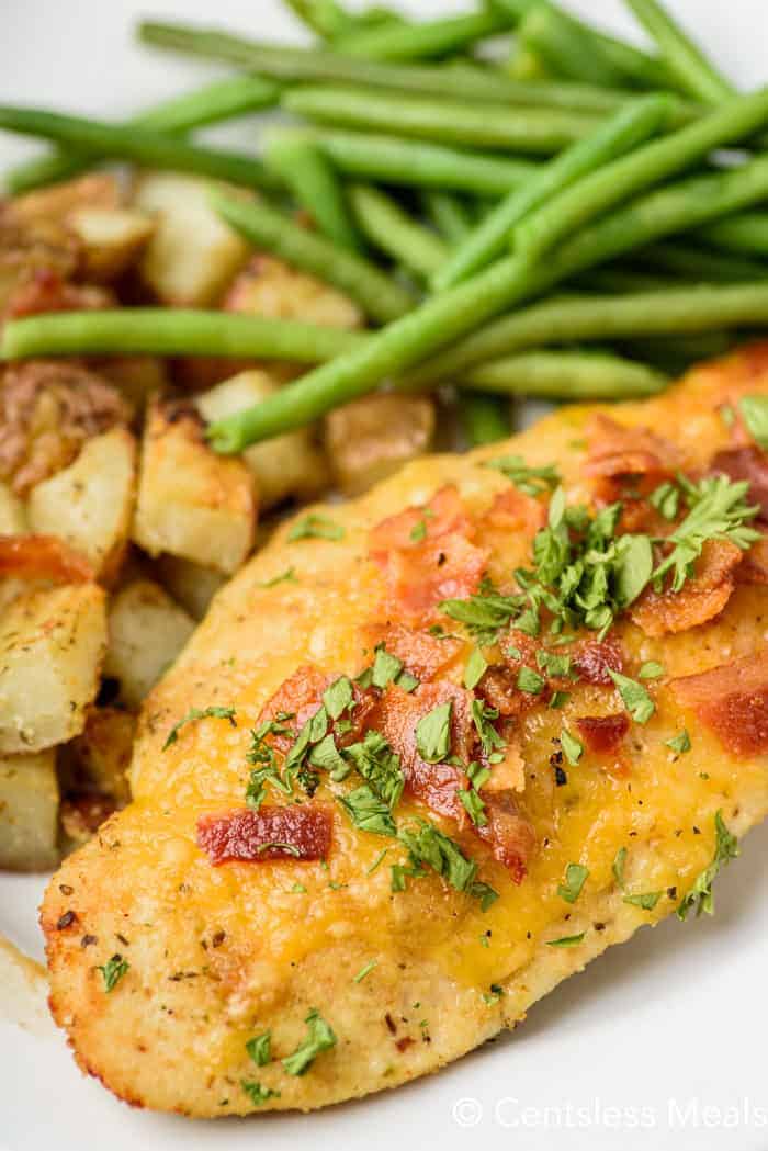 Parmesan crusted chicken on a plate with potatoes and green beans