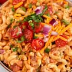 Barbecue chicken macaroni salad in a bowl garnished with tomatoes cheese and onion