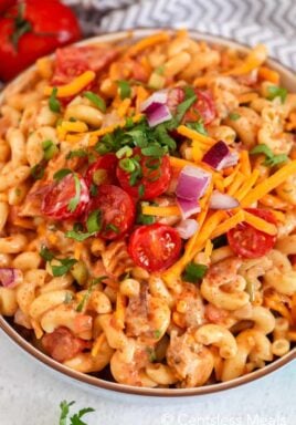 Barbecue chicken macaroni salad in a bowl garnished with tomatoes cheese and onion
