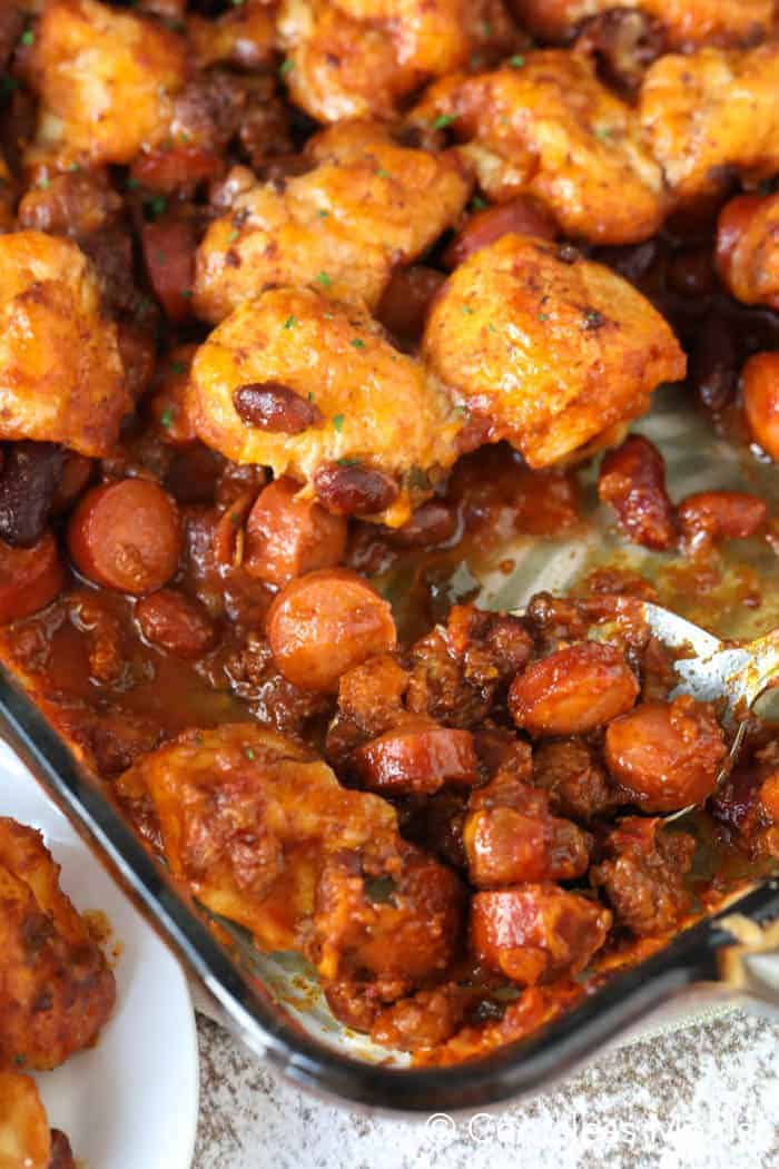 Chili cheese dog bake in a casserole dish with a spoon