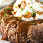 Stove top meatloaf on a white plate with gravy mashed potatoes and parsley