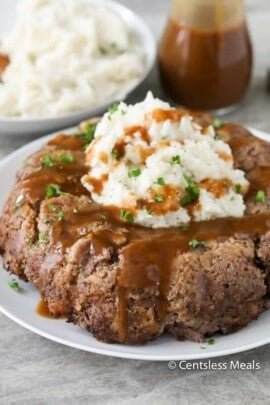 Stove top meatloaf on a plate with mashed potatoes gravy and parsley