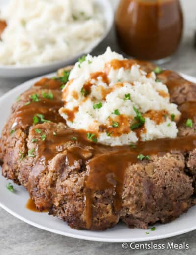 Stove top meatloaf on a plate with mashed potatoes gravy and parsley