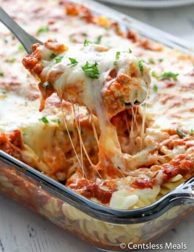 Sour cream noodle bake in a casserole dish with a scoop being taken out with a serving spoon