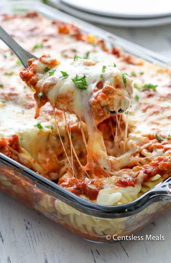 Sour cream noodle bake in a casserole dish with a scoop being taken out with a serving spoon
