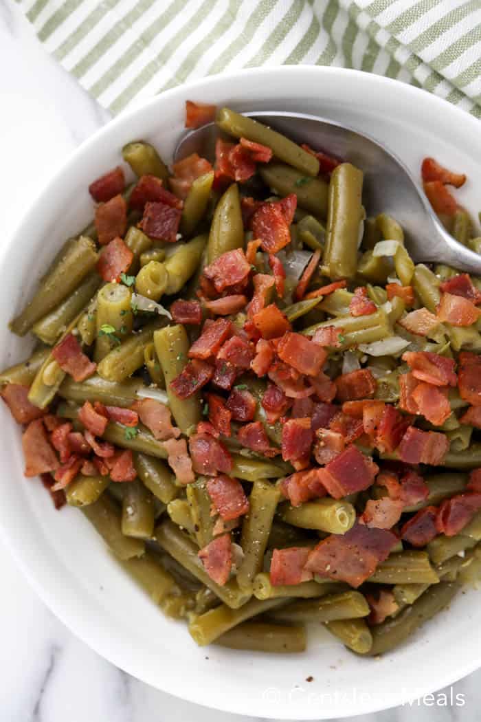 Texas Roadhouse green beans in a white bowl with a metal spoon