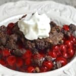 Chocolate cherry dump cake in a bowl topped with whipped cream