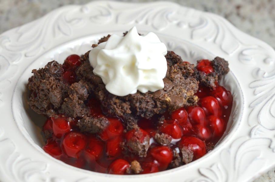 Chocolate cherry dump cake in a bowl topped with whipped cream