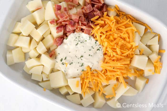 Ingredients for cheesy ranch potatoes with bacon in a white casserole dish