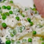 Creamy potatoes and peas on a plate sprinkled with pepper