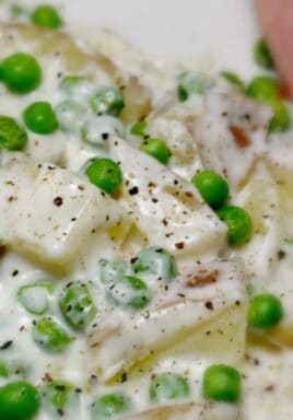 Creamy potatoes and peas on a plate sprinkled with pepper