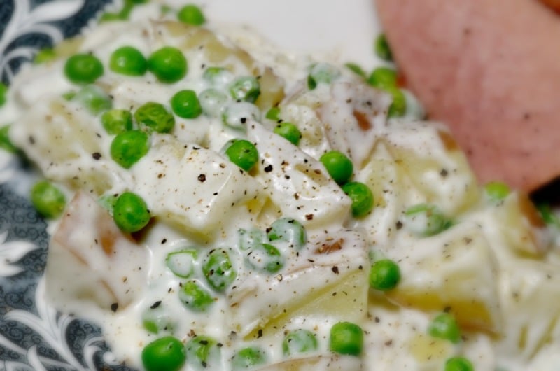Creamy potatoes and peas on a plate sprinkled with pepper