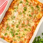 Cream cheese lasagna in a white casserole dish with parsley
