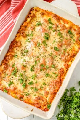 Cream cheese lasagna in a white casserole dish with parsley