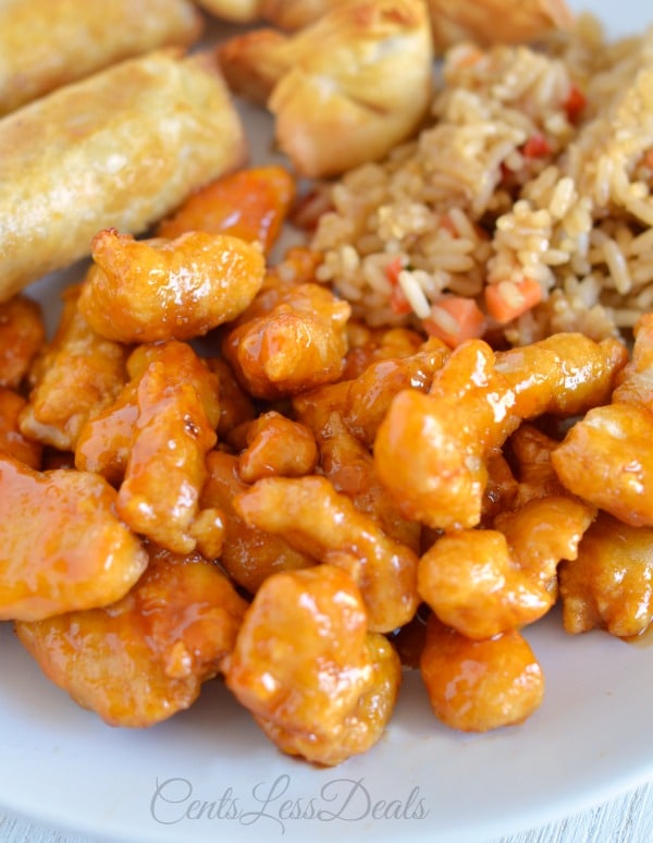 Orange chicken on a plate with rice and spring rolls