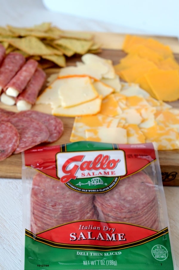 Gallo salame in a package with cheese meat and crackers on a wooden board in the background