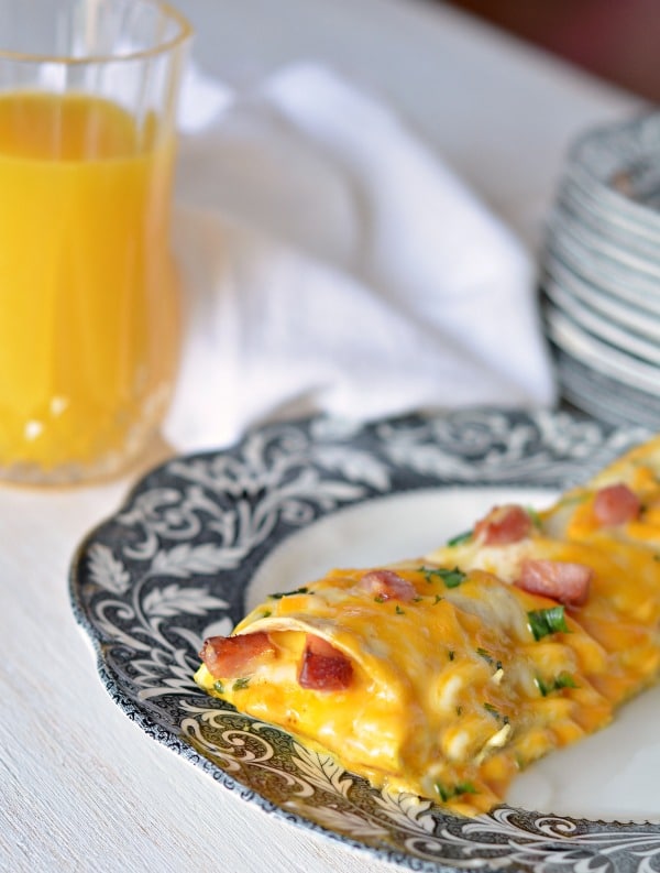 Overnight breakfast enchiladas on a plate with orange juice on the side
