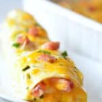 Overnight breakfast enchilada on a plate with ham green onion and parsley on top