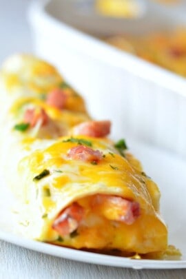 Overnight breakfast enchilada on a plate with ham green onion and parsley on top