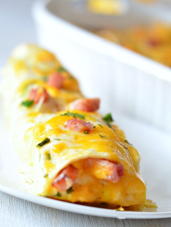 Overnight breakfast enchilada on a plate with ham green onion and parsley on top