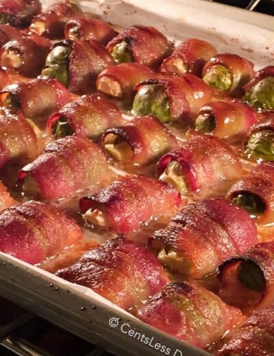 Bacon wrapped brussel sprouts on a baking sheet in the oven
