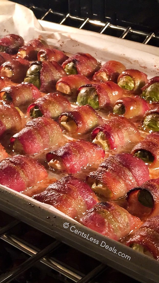 Bacon wrapped brussel sprouts on a baking sheet in the oven