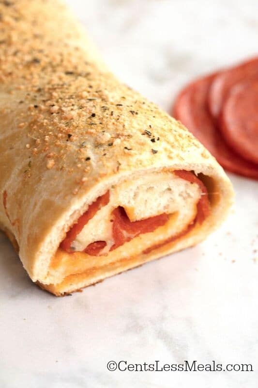 Pepperoni roll on a marble board with pepperoni slices in the background