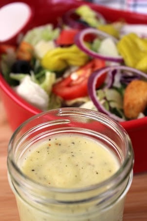 Olive Garden salad in the background with dressing in a mason jar