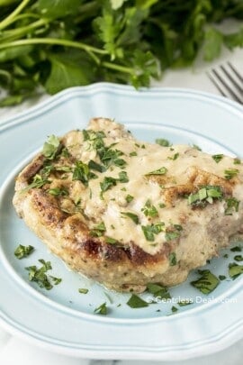 Oven baked pork chop on a blue plate with parsley on top