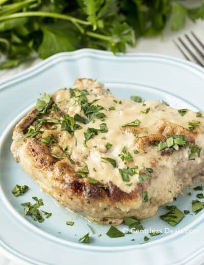Oven baked pork chop on a blue plate with parsley on top