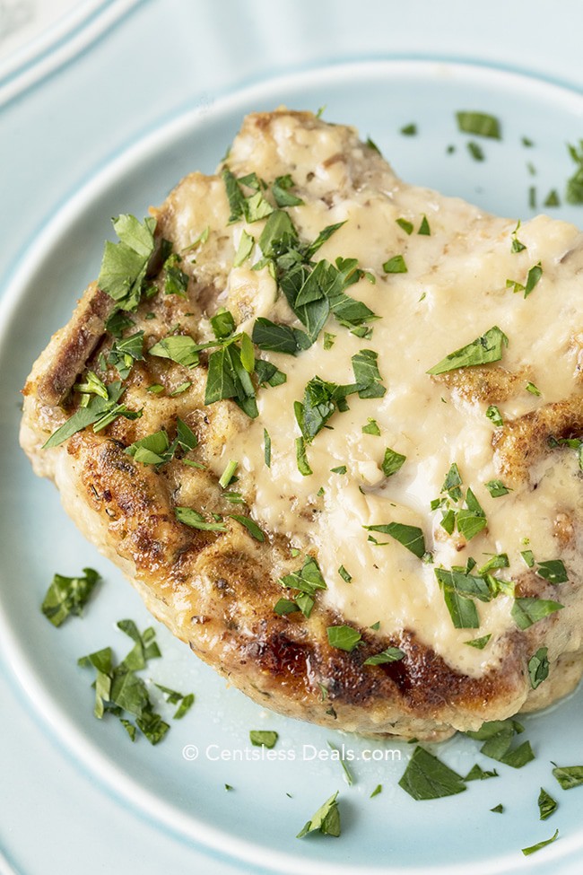 Oven baked pork chop on a blue plate garnished with parsley