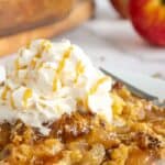 Caramel apple dump cake on a white plate with whipped cream on top