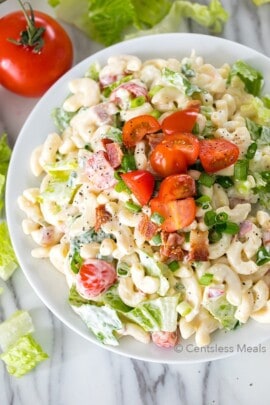 BLT pasta salad in a white bowl with tomatoes on top