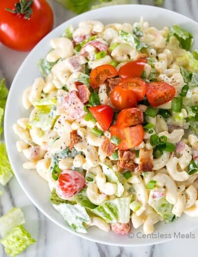 BLT pasta salad in a white bowl with tomatoes on top