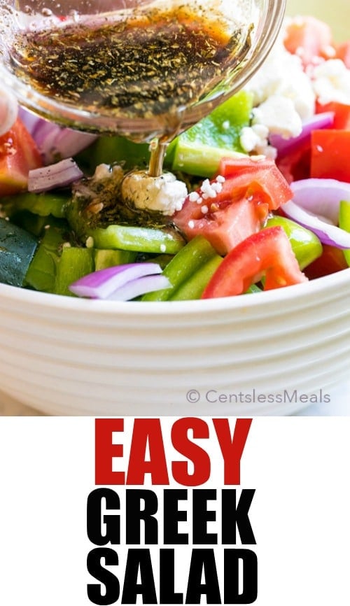 Easy Greek salad in a white bowl with dressing being poured on with writing