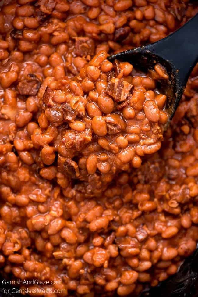 Crock-Pot baked beans with a black spoon