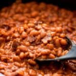 Crock-Pot baked beans being scooped up with a spoon