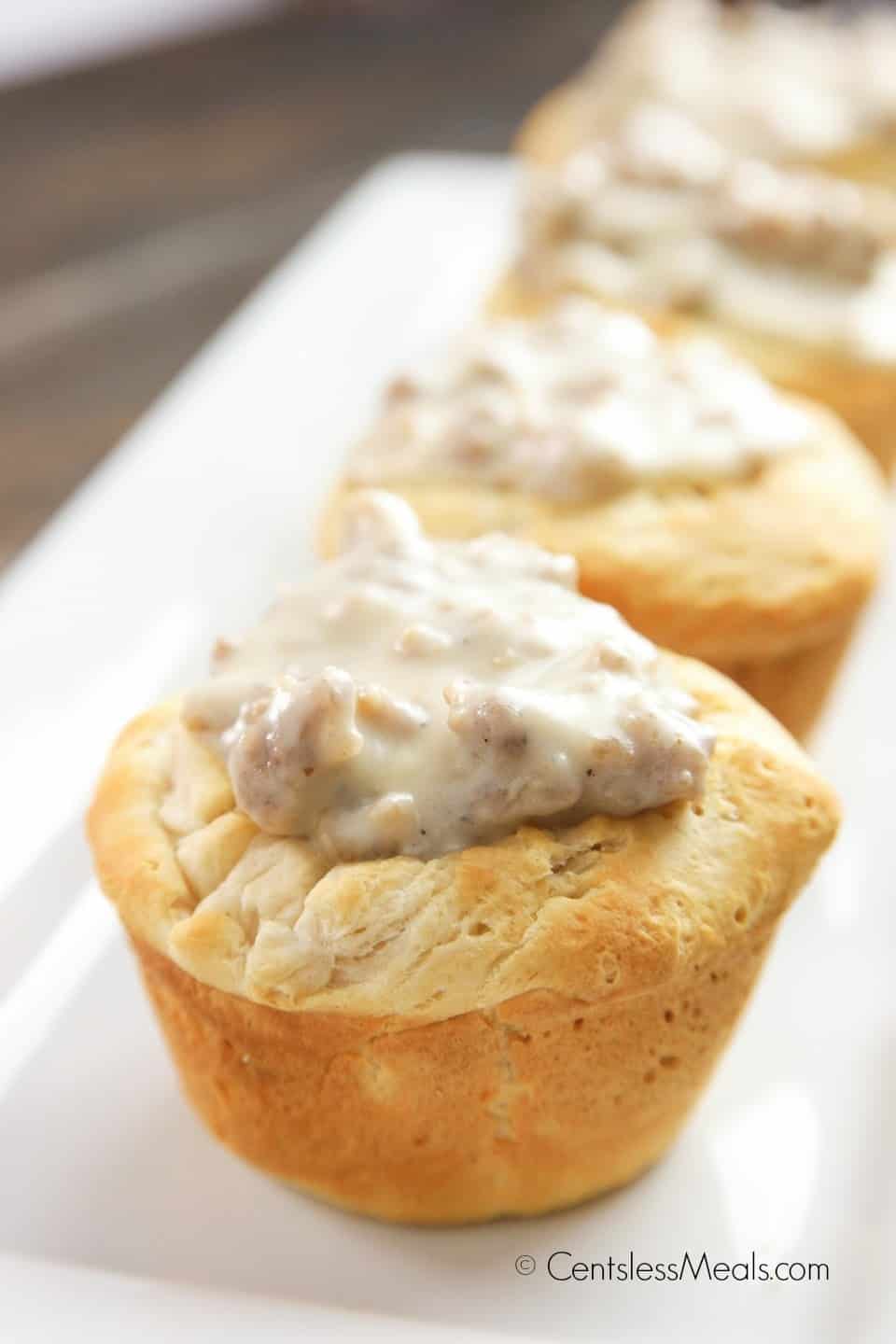 Biscuit and gravy cups on a white serving plate with gravy on top of the biscuit