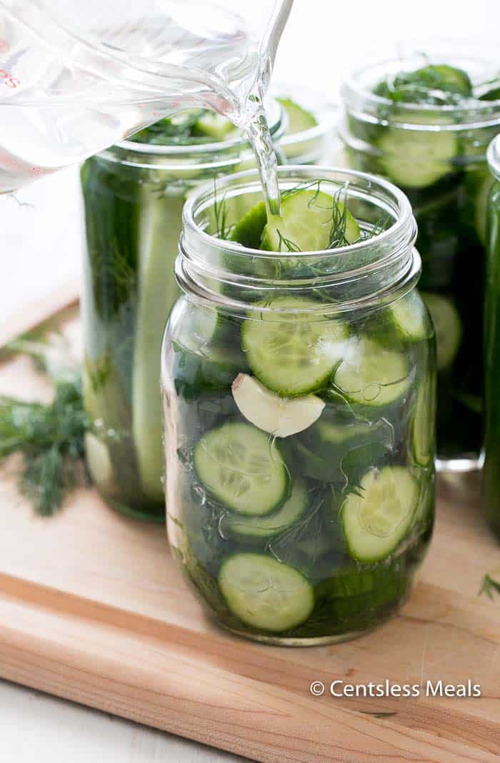 Refrigerator Dill Pickles in mason jars with water being poured in