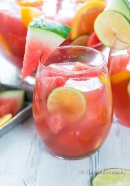 Watermelon sangria in a glass garnished with watermelon lime and lemon slices