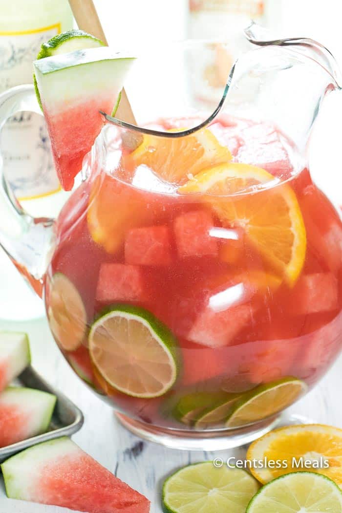 Watermelon sangria in a glass pitcher garnished with watermelon lime and lemon