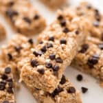 No bake chocolate chip granola bars on parchment paper with chocolate chips on the side