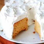 Pumpkin angel food cake on a white plate with a piece taken out