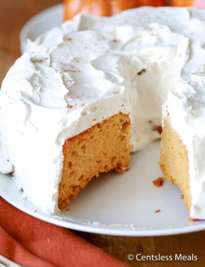 Pumpkin angel food cake on a white plate with a piece taken out
