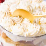 Caramel apple trifle in a dish with some being scooped out with a gold spoon