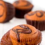 Nutella pumpkin muffins on a wooden board with one out of the wrapper